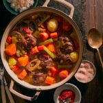 Pepper pot stew in a dish on a rustic, wooden table