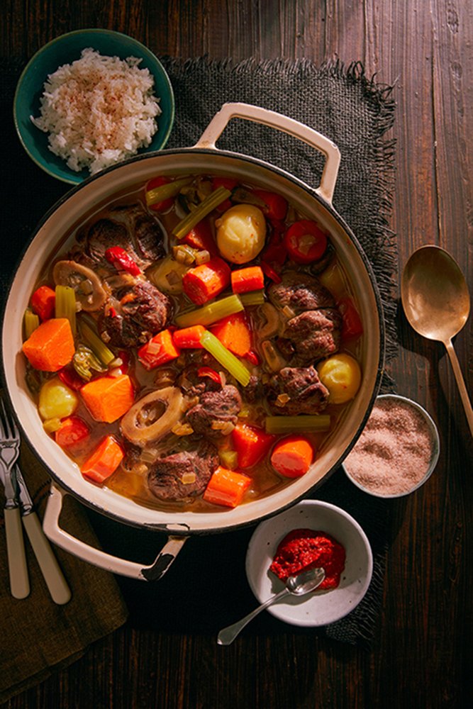 Pepper pot stew in a dish on a rustic, wooden table 