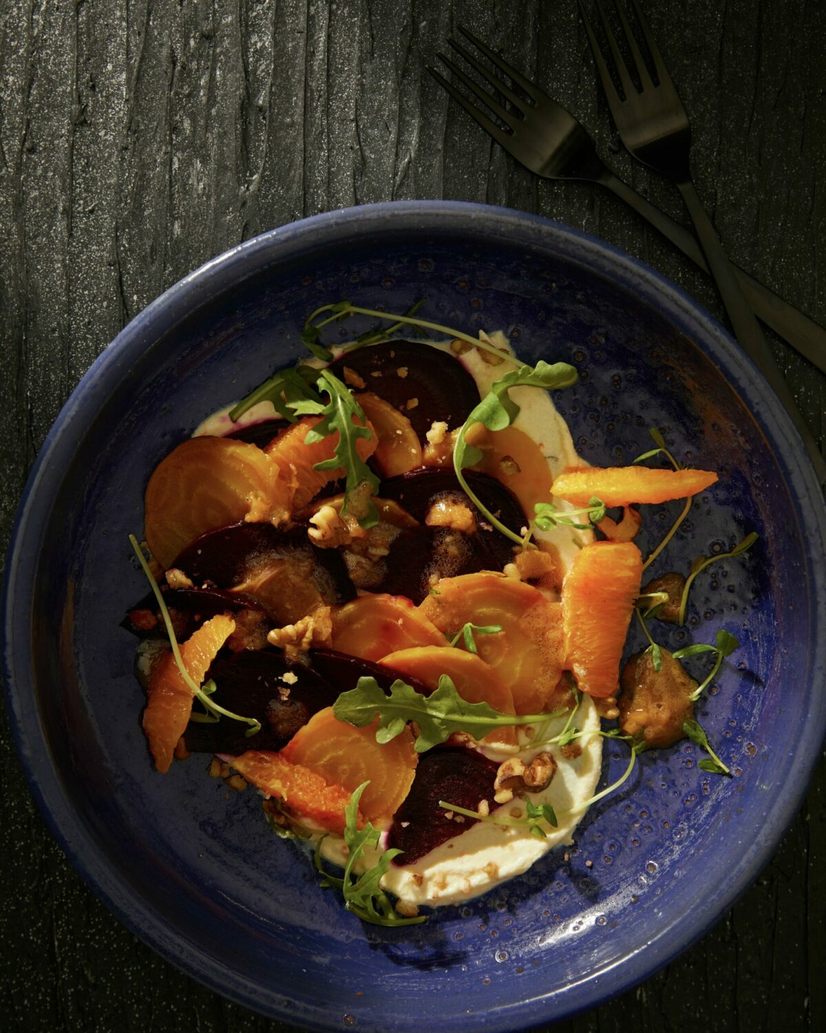 Sliced beets on a blue plant with various greens and nuts throughout. 