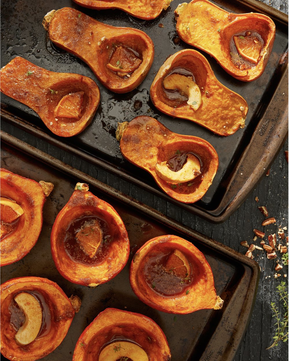 A variety of roasted squash on a baking sheet filled with orange slices and spices.