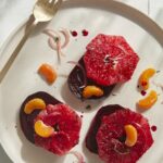 Braised Beet and Grapefruit Salad on a white plate with a steel fork at the corner