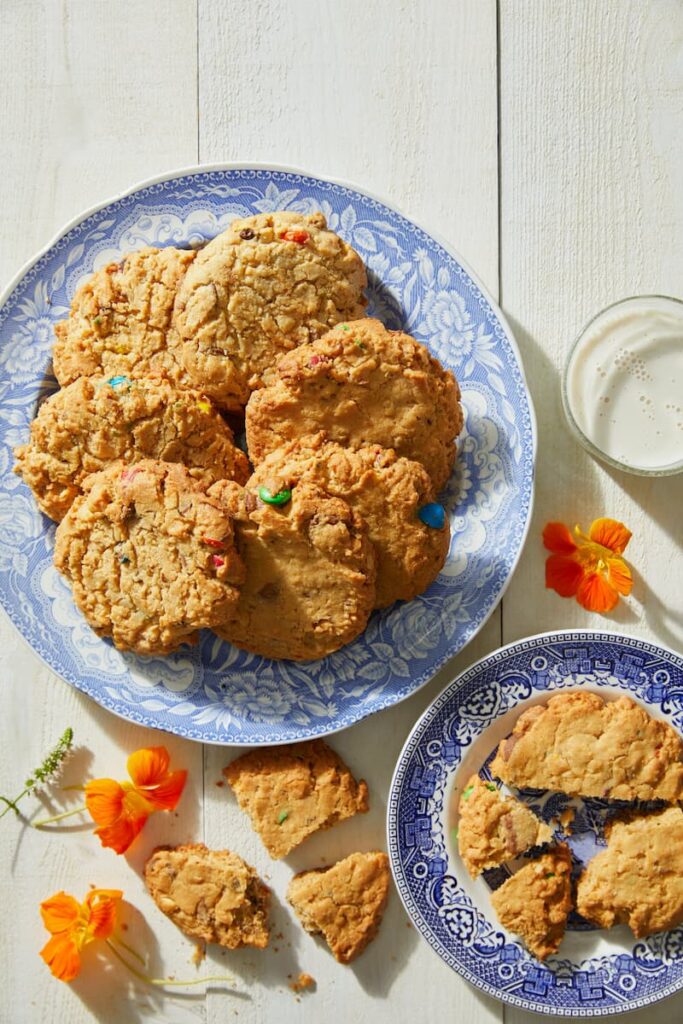 Kitchen Sink Cookies served on two stylish, ceramic plates with flowers on the side