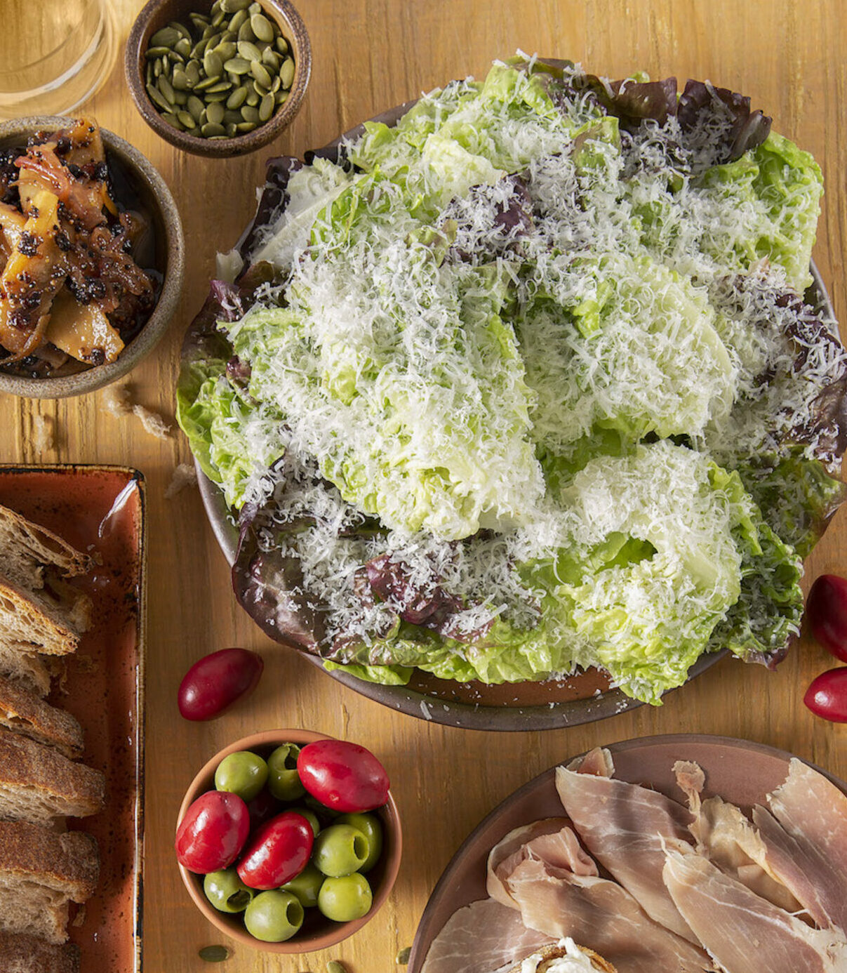 A lush salad green and purple in color sits on a table surrounded by tomatoes, bread, and meat. Easy Vinaigrette Recipe