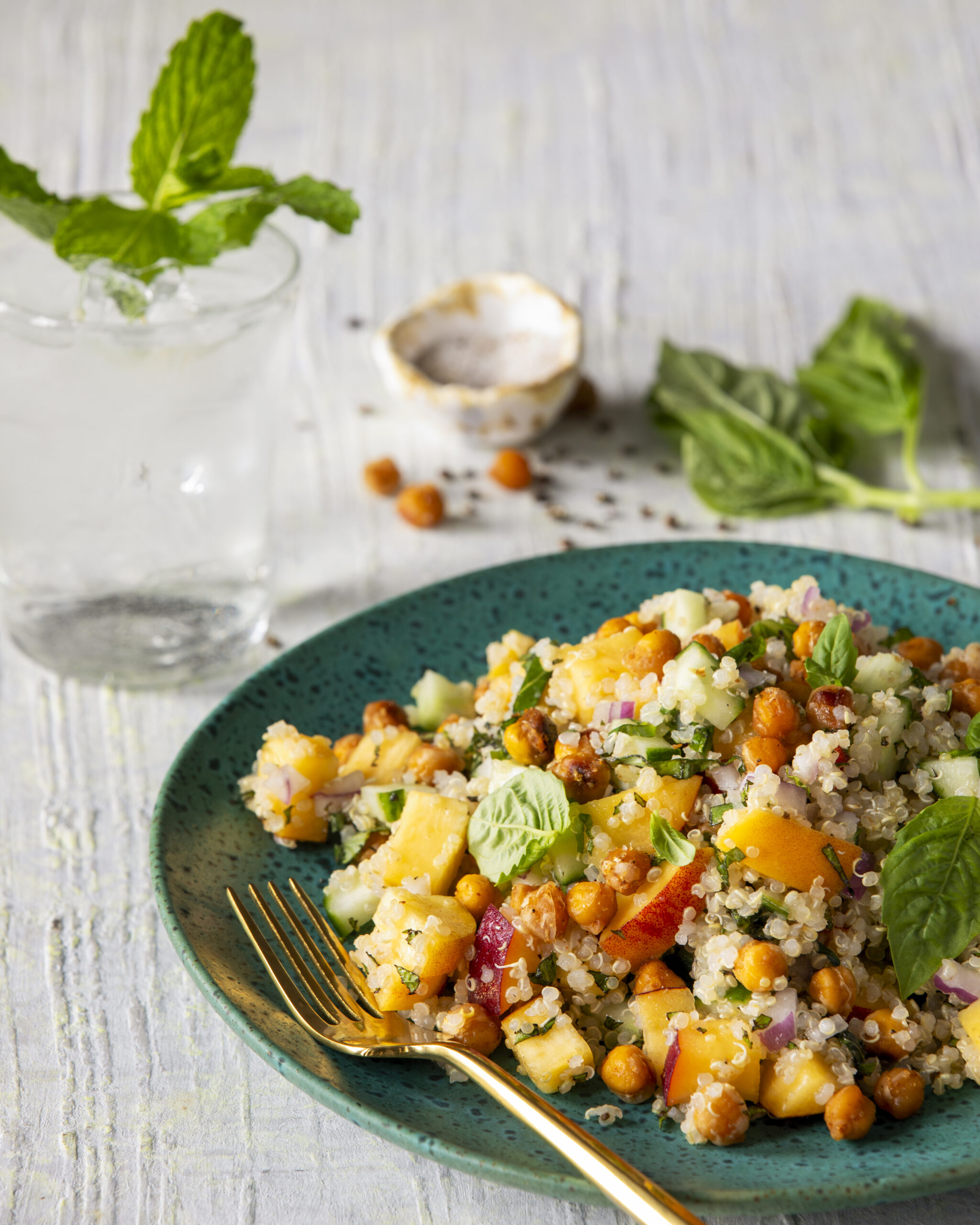 A teal speckled serving dish white background and a large portion on quinoa and peach salad.