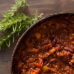 An aerial view of a bowl of chili, red in color