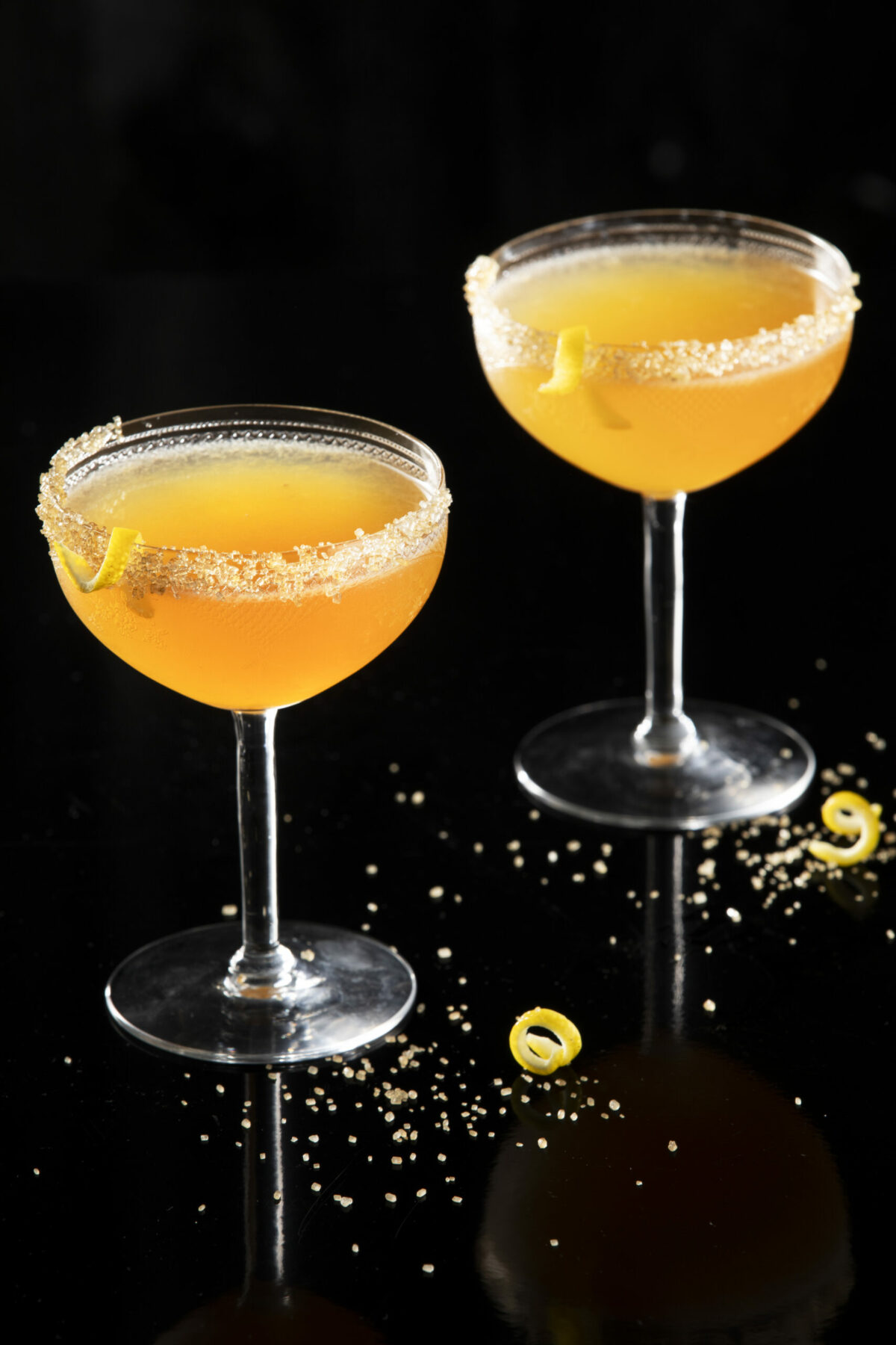 Two orange, yellow cocktails in coupe glasses. sidecar cocktail