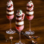 Three champagne flutes filled with peppermint desserts, pink, white, and brown stripes in color.