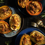 Three different shades of blue plates with bread pudding stuffed small halved squashed with rosemary and red peppercorn garnish around the plates