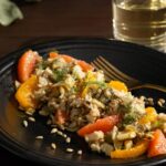 Brown Rice and Lentil Salad with Citrus & Roasted Fennel served in a black plate with a steel fork