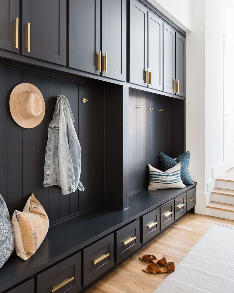 A mudroom updated for 2024 design trends with dark cabinets and hangers holding light jackets and hats.