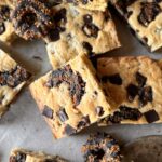 A pile of Samoas Blondies lay on a marble table top with lightly toasted tops.