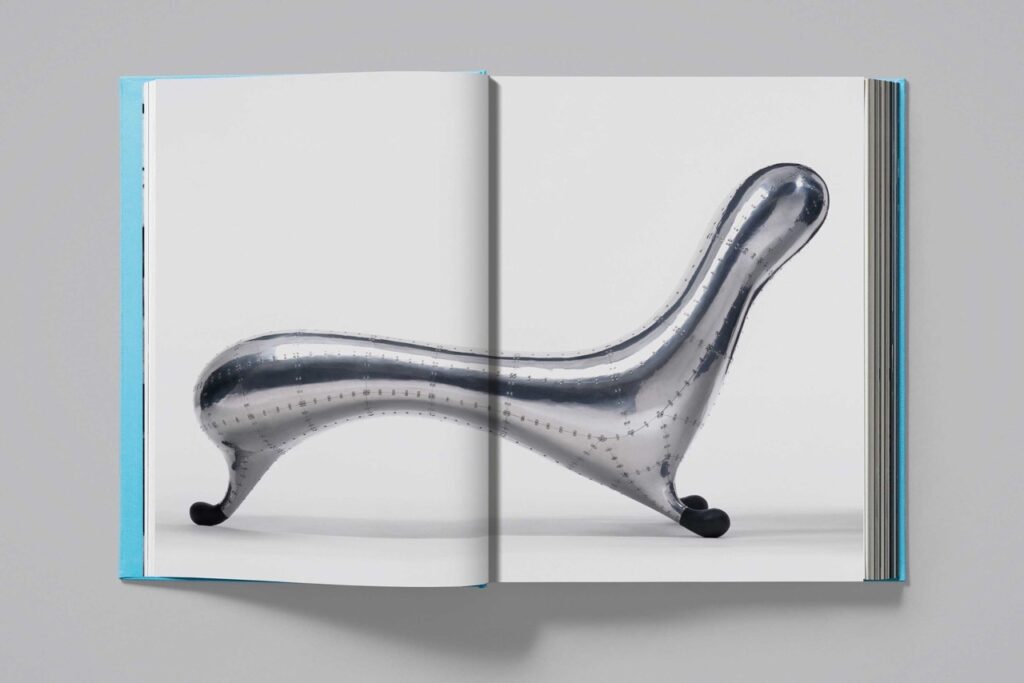 Two pages of Marc Newson Works 84-24 sits face up shows a silver chair across the two pages.