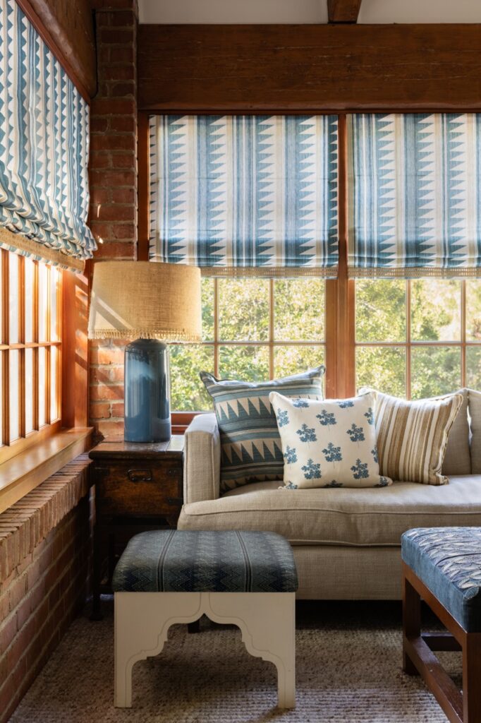 An interior by Nathan Turner with wood walls, a blue and white couch and other blue and white accessories like a small table and lamp.