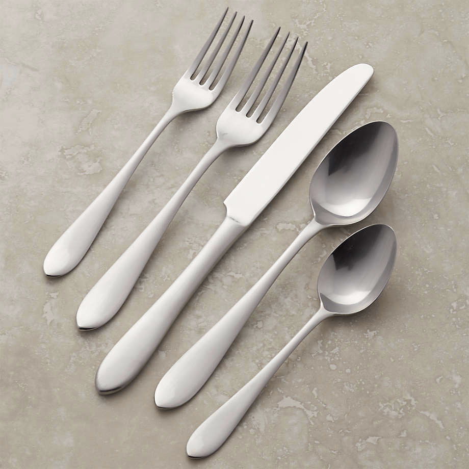 A set of two forks, a knife, and two spoons on a beige background