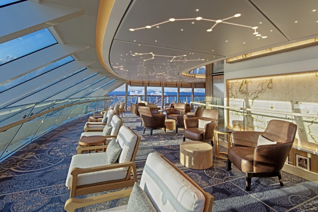 An interior of the Viking Cruise ship with plush chairs looking out a glass window to the ocean.