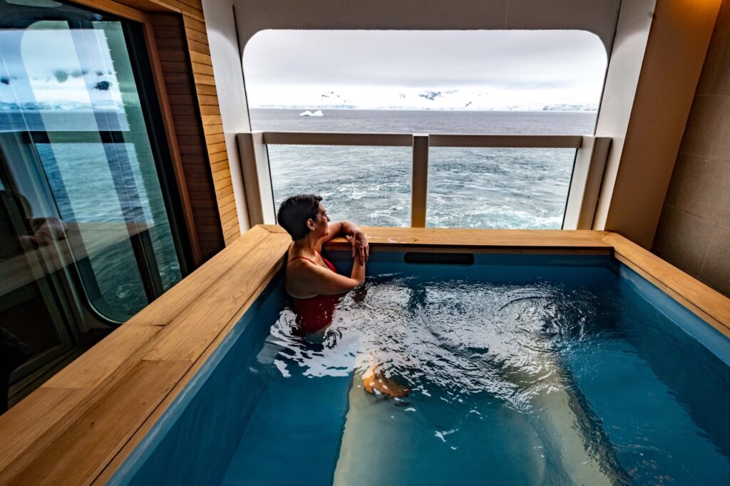 A man sits in the Viking Cruise spa pool that has a looking glass outside to Antarctica.