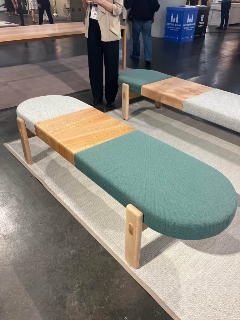 A long, almost surfboard shape bench in white, wood, and teal colors sits on the floor of New York Design Week.