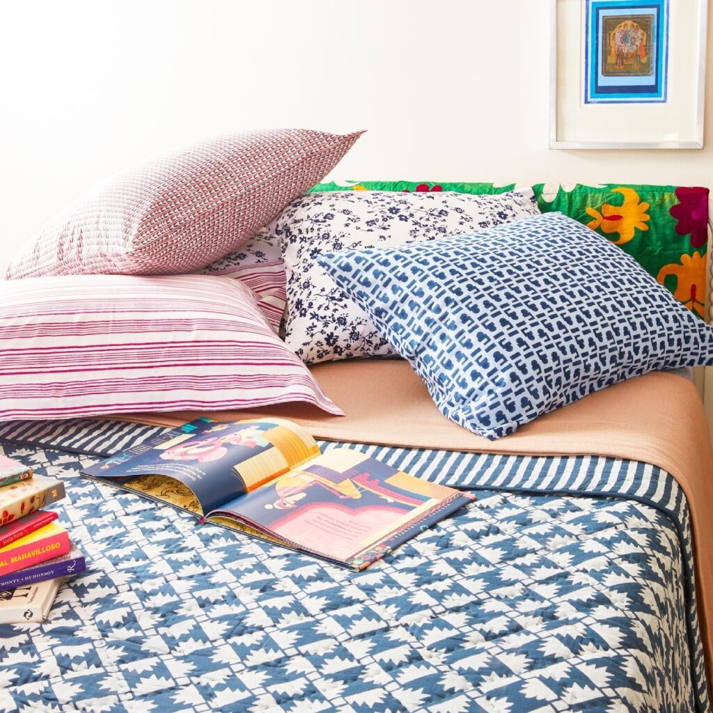 A bed designed from products at Layla fashion store in Boerum Hill featuring a pattern blue bed sheet and pillow plus two pink pattern pillows.