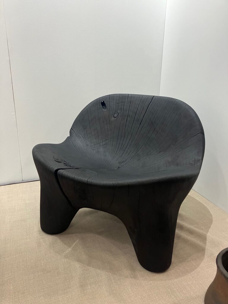 A small black chair sits in the corner of a room at New York Design Week.
