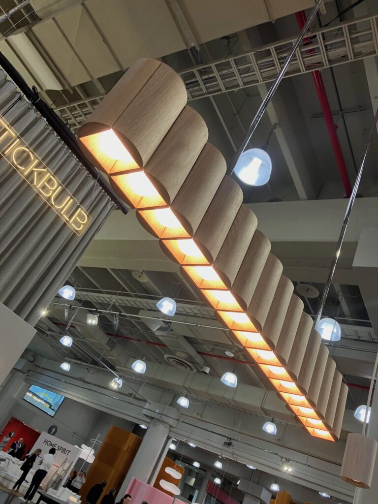 A line of lights by stickbulb shine down from the ceiling in the ICFF at New York Design Week.