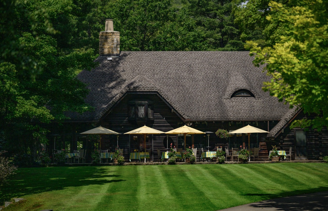 The outside of The Lodge at Glendorn with umbrellas at outside tables.