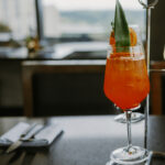 A summer spritz cocktail, colored red and with a green leaf for garnish