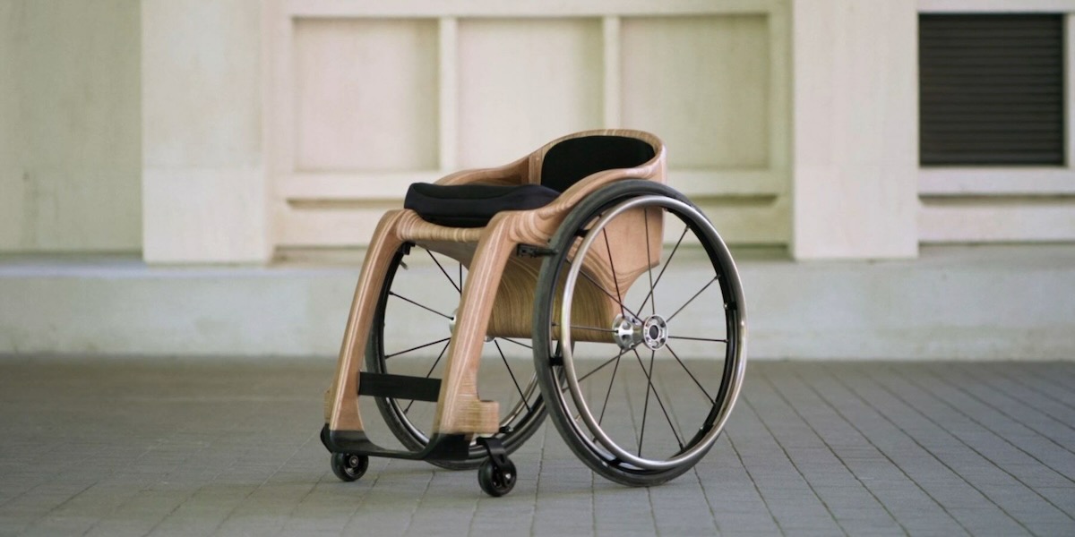 A wooden wheelchair by apollo sits against a city street background.