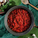 A plate of bright red tomato sauce on a verdant green background