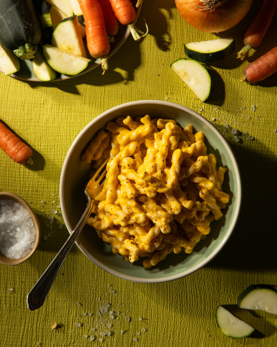 A bowl of mac and cheese surrounded by vegetables