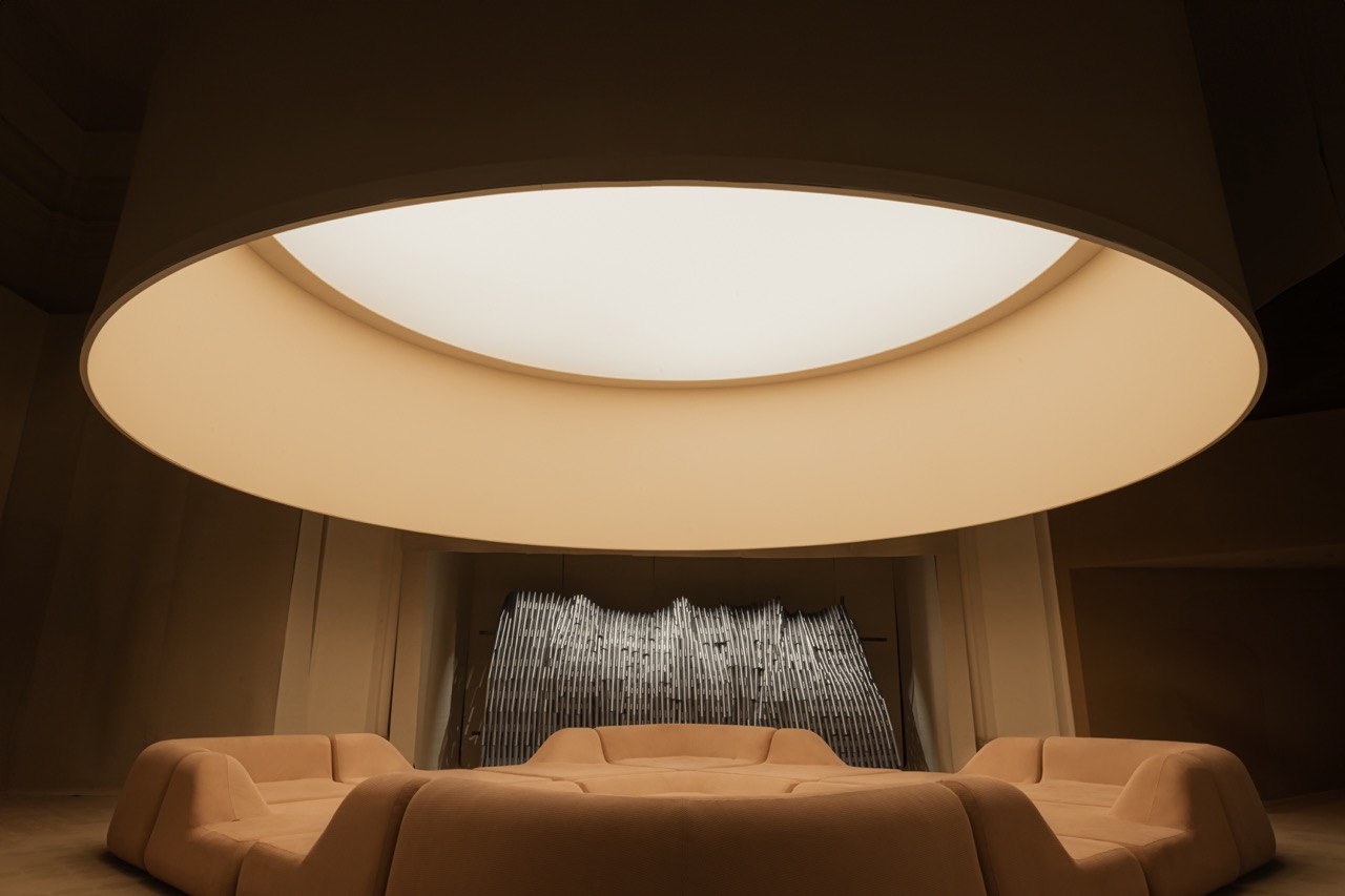 A large light casts over a comfy conversation circle in an orangish brown color.