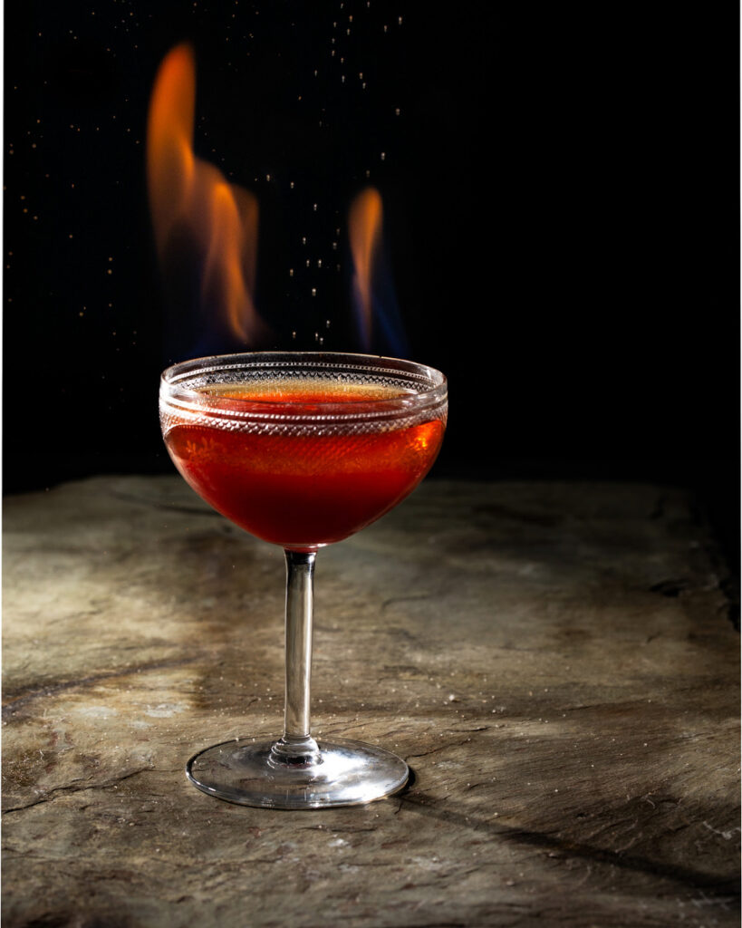 A cocktail for Gladiator II, bright red in a coupe glass on a white background