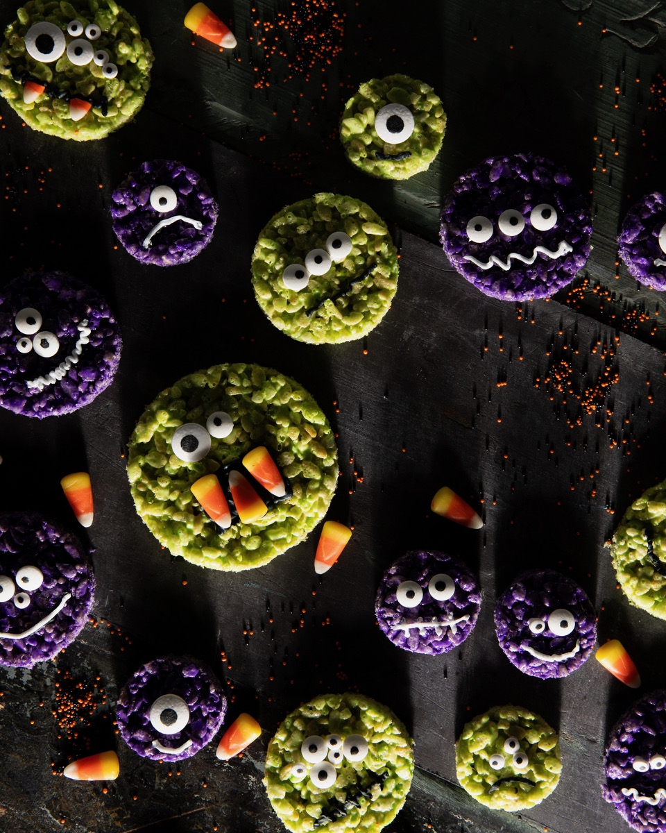 A set of monster rice krispy treat Halloween dessert cookies with candy eyes and candy corn on them