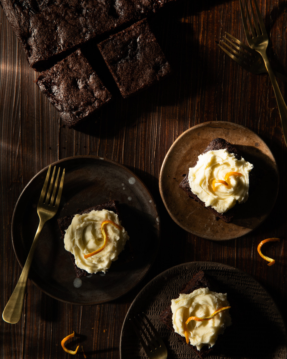 Three brownies frosted with luxardo buttercream frosting and topped with orange zest