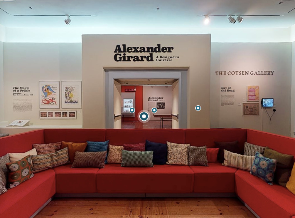 A red couch with the Alexander Girard sign above it, viewable in the virtual exhibitions