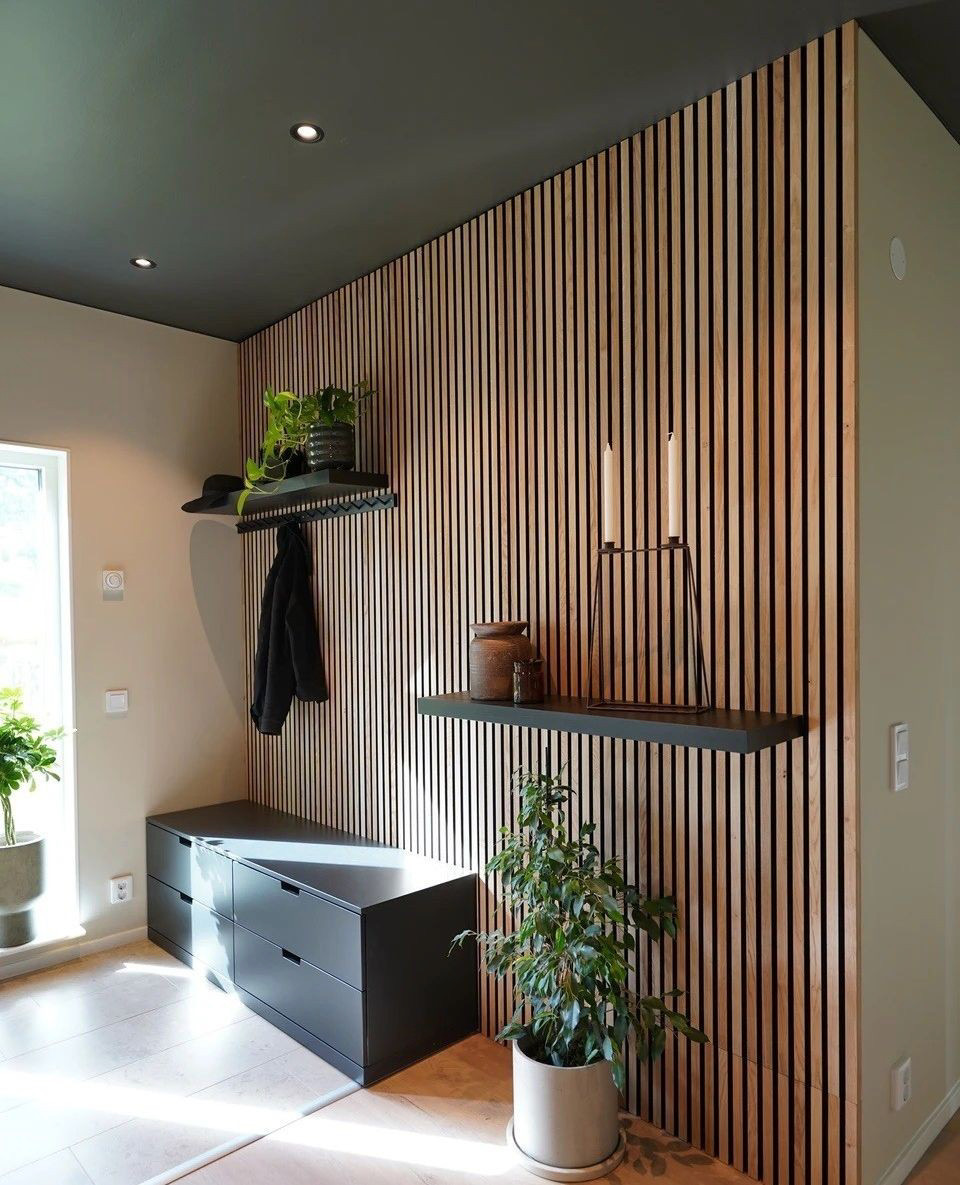 A dark-colored wood wall with plants and shelving units on top of it 