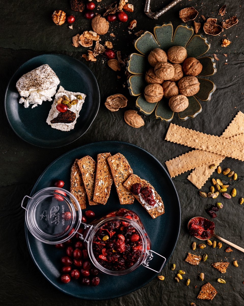 An assortment of holiday foods including a plate with white cheese and cranberry sauce.