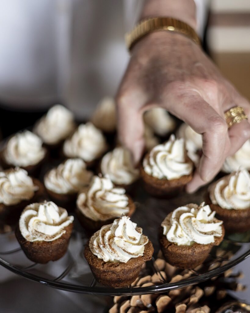 A person picks up a cookie cup from a plate of cookie cups decorated with a swirl of icing. 