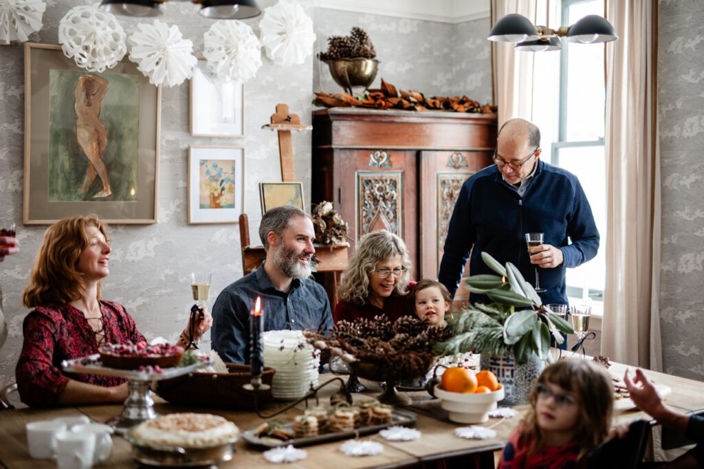 A family and a young girl gather around a table full of holiday dessert recipes.