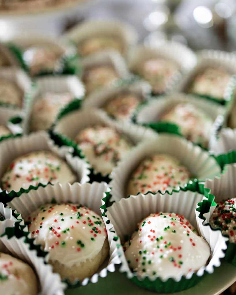 Small round balls of Lemon Ricotta Cookies sit in little green wrappers.