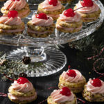 A plate of pistachio sandwich cherry cookies on a piece of glassware