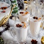 A set of festive coquito cocktail glasses staged on a holiday-themed table