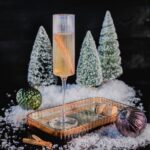 A champagne flute sits on a staged Christmas set for this champagne spiced cocktail