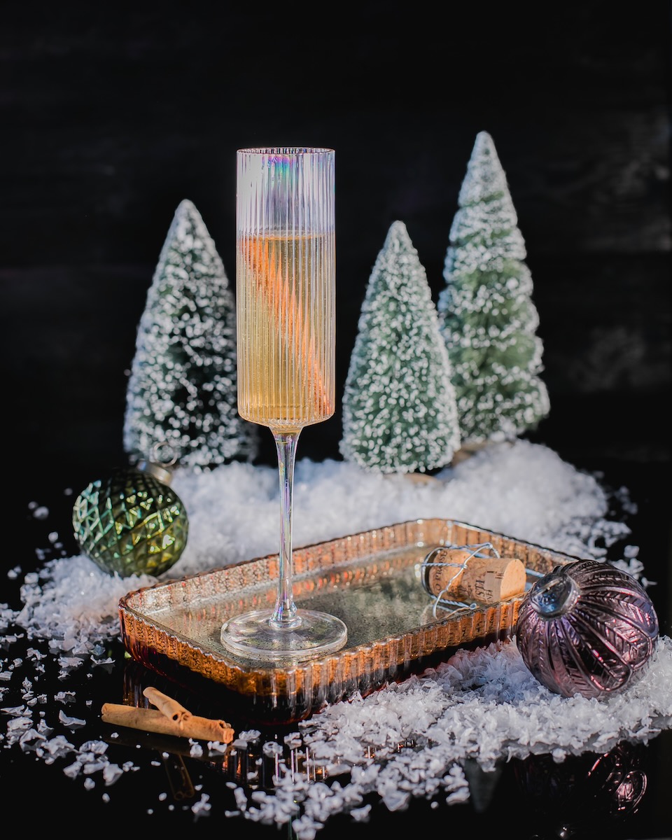 A champagne flute sits on a staged Christmas set for this champagne spiced cocktail