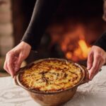 A turnip gratin on a table with a white tablecloth, held by Melissa Martin