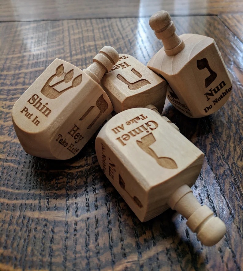 Wooden dreidels on a table, with Hebrew lettering on them 