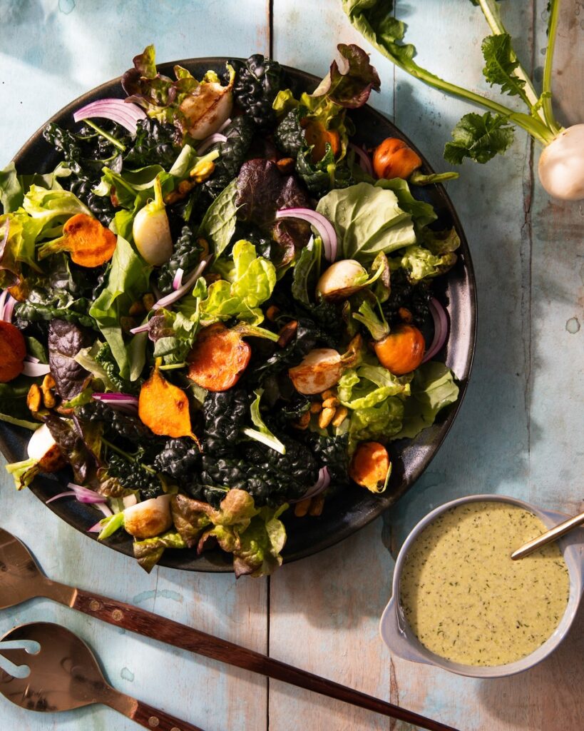 A plate of salad on a white background, paired with vinaigrette.