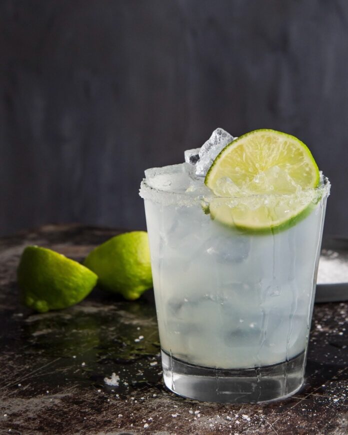 A classic margarita recipe by Maggie Weaver, garnished with lime.