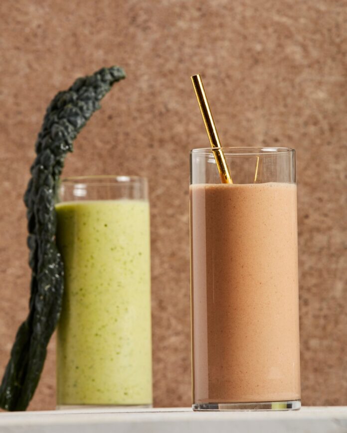 Pittsburgh Pirates smoothie, one brown with a gold straw sits beside a green smoothie both against a brown background.