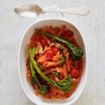 A red lentil pasta in a white dish on a white background.