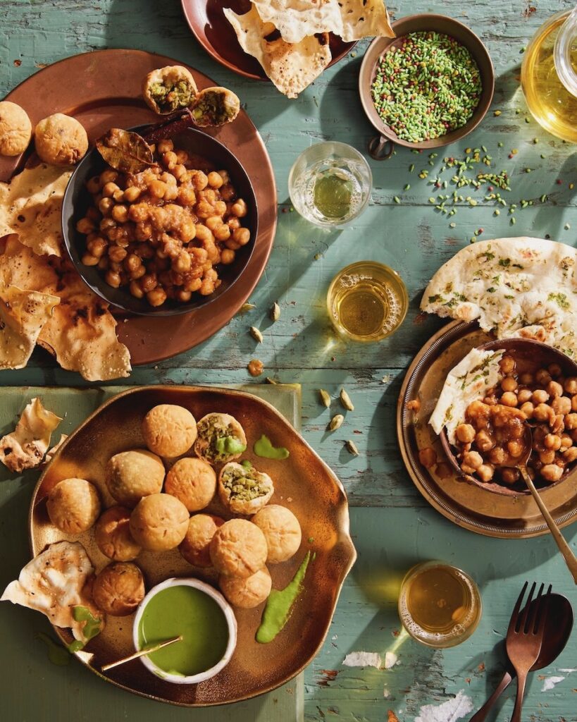 Kachori fritters staged on a blue piece of wood surrounded by colorful sauces.